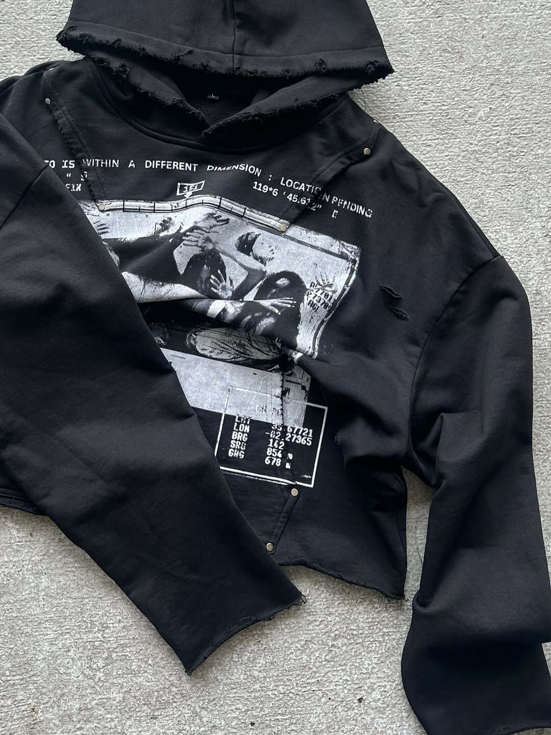Black oversized hoodie with artistic distressing and graphic print, featuring metal hardware and raw cut hem.